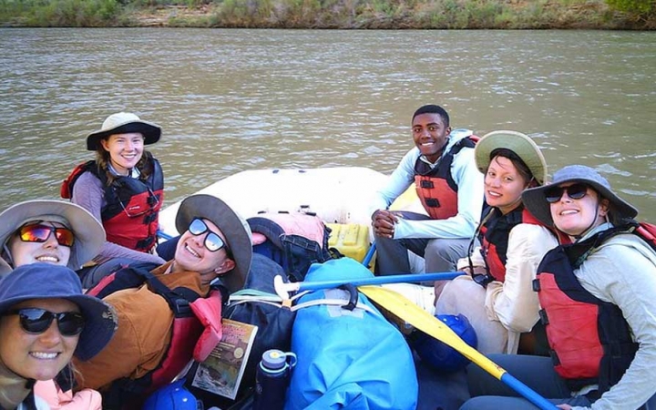 a group of gap year students smile while sitting in a raft on a river in the southwest